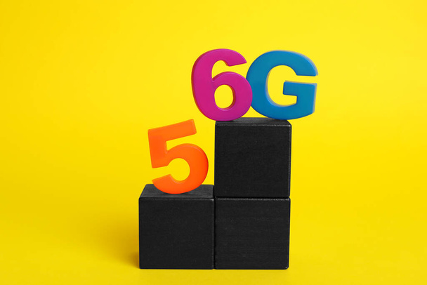 Концепція Інтернету. Чорні дерев'яні куби з 5 і 6G на жовтому тлі - Фото, зображення