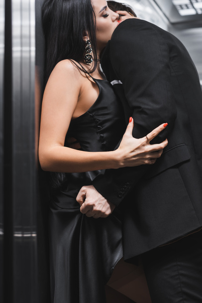 Man in suit taking off dress from sexy girlfriend in elevator  - Фото, изображение