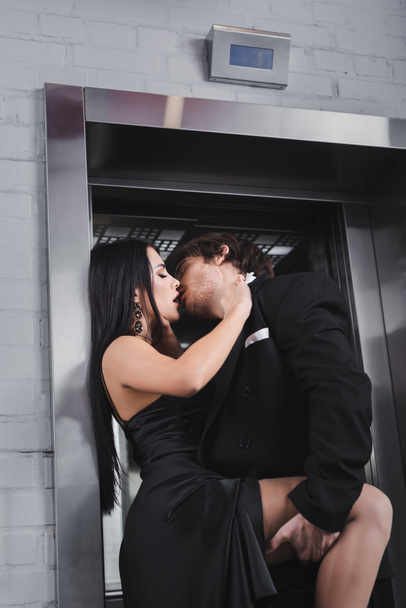 Passionate young couple in formal wear kissing near elevator  - Photo, Image