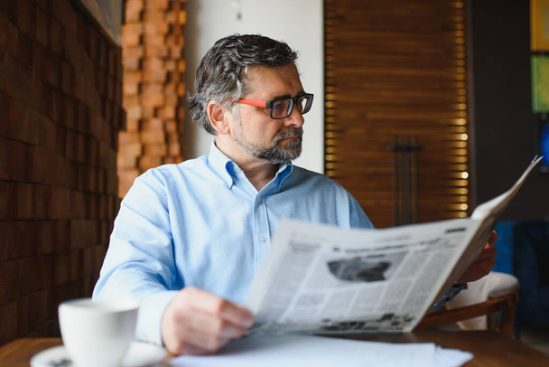 Newspaper in the morning. Senior businessman at his office riding newspapers - Foto, Imagem