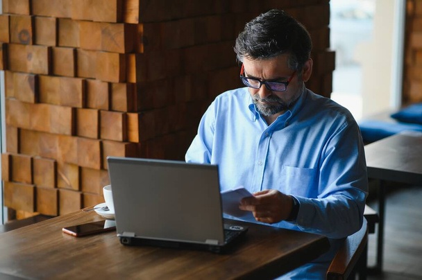 Geschäfts-, Technologie- und Personalkonzept, Senior-Geschäftsmann mit Laptop trinkt Kaffee in modernem Café - Foto, Bild
