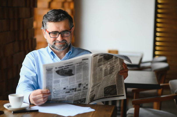 active senior man reading newspaper and drinking coffee in restaurant. - Fotoğraf, Görsel