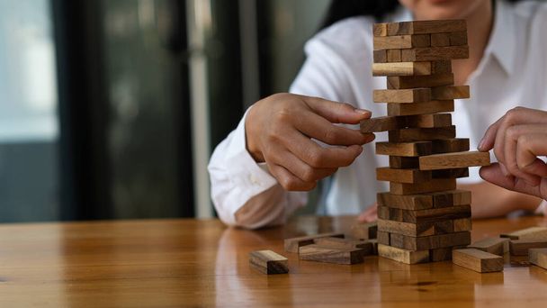 オフィスの木製のブロックで塔を構築し、アジアの実業家の手の塔は、ゲームをプレイし、彼女の机に座っている。将来の従業員の計画プロジェクトや事業戦略の策定、意思決定 - 写真・画像