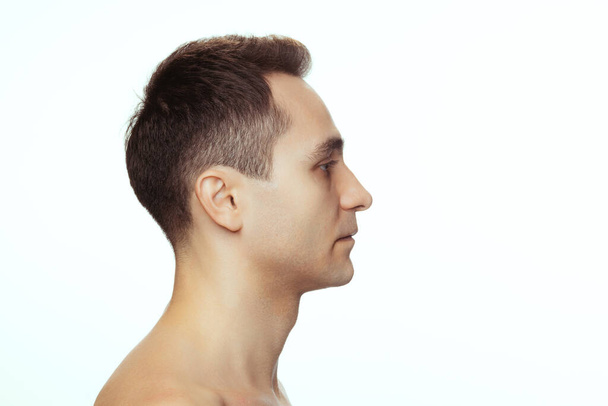 Портрет молодого человека без рубашки, смотрящего в сторону, позирующего на белом фоне студии - Фото, изображение