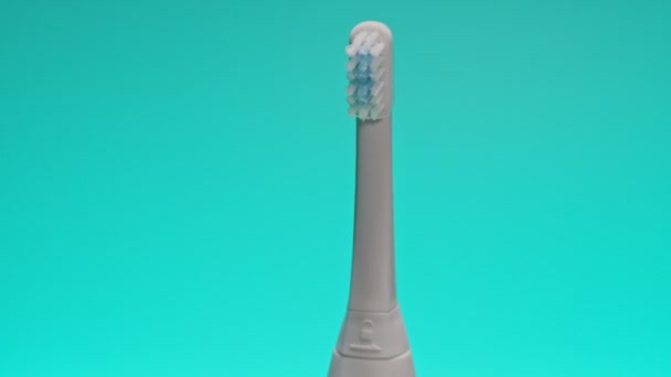 Ηλεκτρική οδοντόβουρτσα υπερήχων σε μεταβαλλόμενο φόντο χρώμα. - Πλάνα, βίντεο