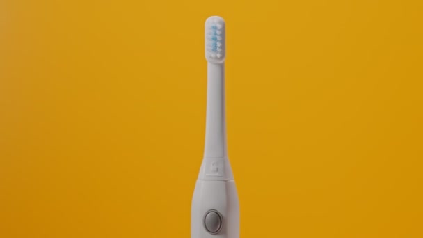 Brosse à dents électrique à ultrasons sur fond jaune. - Séquence, vidéo