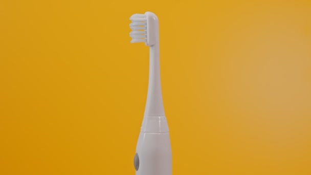 Elektrische ultrasone tandenborstel op gele achtergrond. - Video