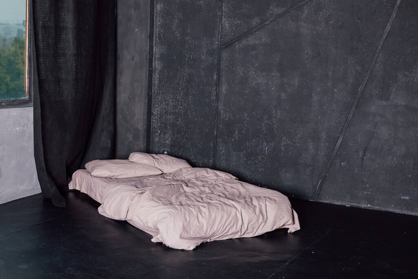 Postel s bílou postelí stojící v tmavém pokoji v blízkosti okna - Fotografie, Obrázek