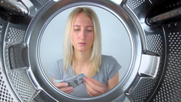 housewife counts money near washing machine and leaves them to wash. Laundering or saving family budget on washing clothes. It is expensive to wash and repair washing machine under warranty. Service. - Footage, Video