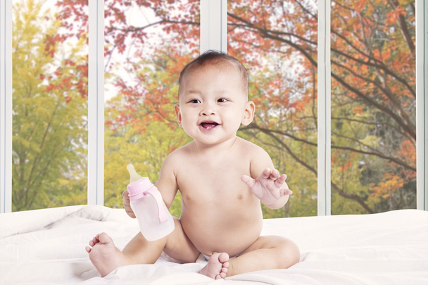 Baby playing on bed with milk bottle - Φωτογραφία, εικόνα