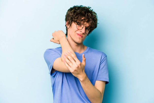Nuori valkoihoinen mies eristetty sinisellä pohjalla, jolla on niskakipu stressin, hieronnan ja koskettamisen vuoksi. - Valokuva, kuva