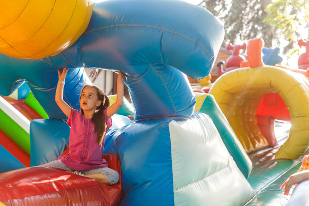 Happy little girl having lots of fun on a jumping castle during sliding. - Photo, Image
