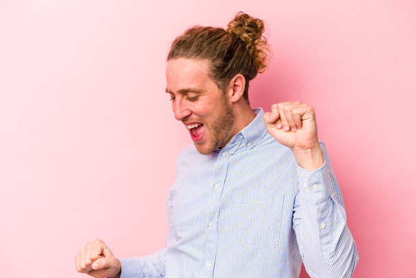 Young caucasian man isolated on pink background dancing and having fun. - Photo, Image