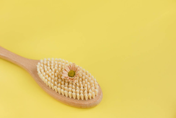 Banner with hair brush, anti-cellulite brush with flower on a yellow background with copy space, place for text. Eco cosmetics products and tools on a yellow background. Zero waste, Plastic free. Sustainable lifestyle concept. - Photo, Image