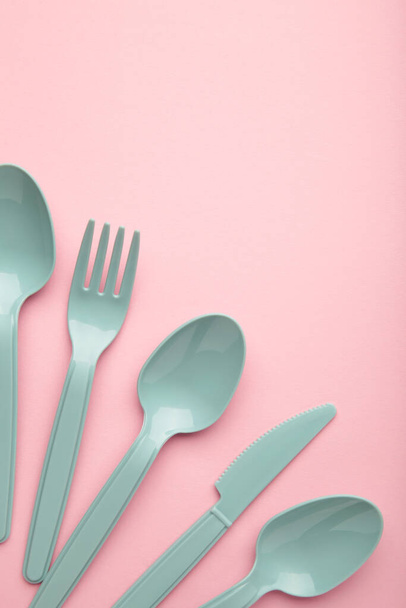 Molte forchette, cucchiai e coltelli plasic blu su sfondo rosa con spazio per la copia - Foto, immagini