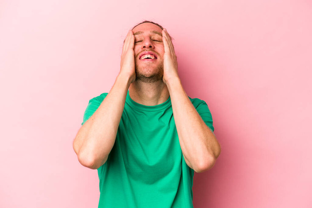 Young caucasian man isolated on pink background laughs joyfully keeping hands on head. Happiness concept. - Photo, Image