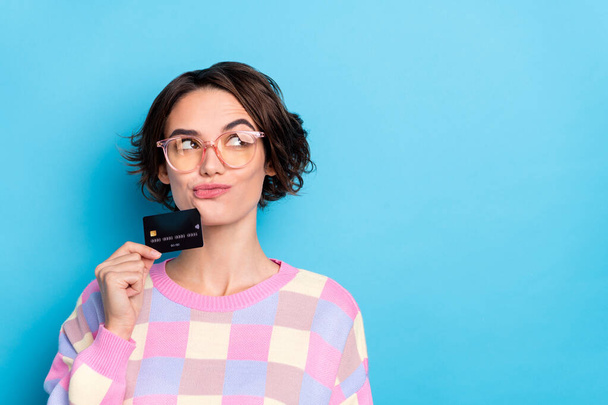 Photo of thinking young brunette lady hold card look empty space wear eyewear plaid pullover isolated on blue background - Photo, Image