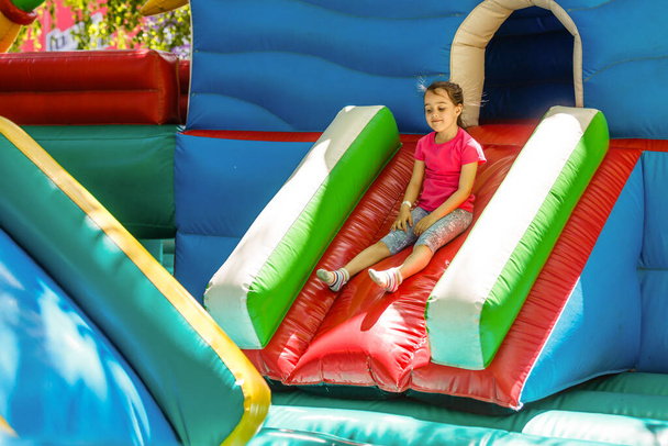 Happy little girl having lots of fun on a jumping castle during sliding. - Photo, Image