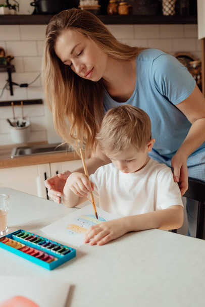 Mother and toddler boy makes a postcard for Easter holiday. Easter holiday together at home. Thanksgiving traditions and childhood togetherness concept. - Foto, Imagem