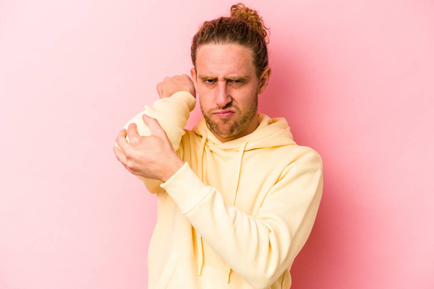 Young caucasian man isolated on pink background having a neck pain due to stress, massaging and touching it with hand. - Photo, Image