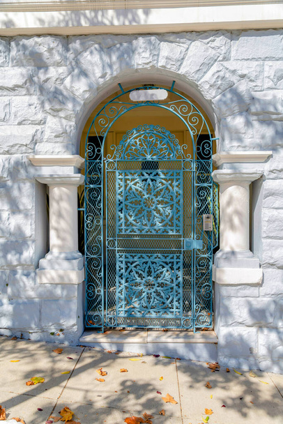 Arched blue metal gate with pillars on both sides in San Francisco, California. Entrance of a house with painted stone walls and doorbell at the metal gate with a view of the front door. - Photo, Image