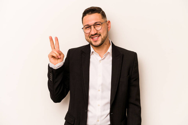 Επιχειρηματίας ισπανόφωνος άνθρωπος απομονώνονται σε λευκό φόντο χαρούμενη και ανέμελη δείχνει ένα σύμβολο ειρήνης με τα δάχτυλα. - Φωτογραφία, εικόνα