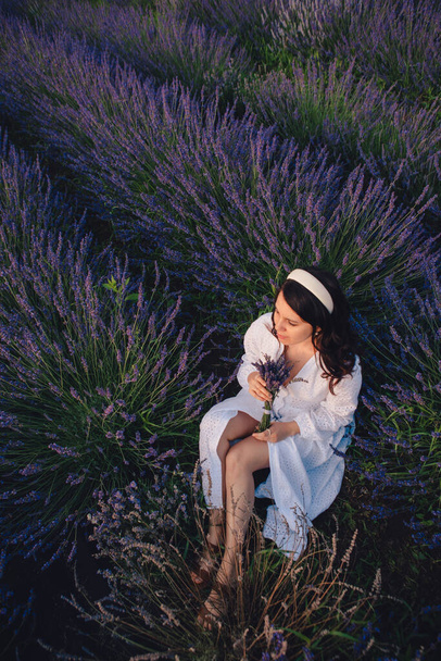 prachtige vrouw in witte jurk op lavendelveld zonsondergang tijd - Foto, afbeelding
