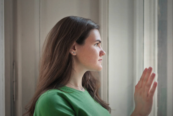 portrait of young woman while looking out the window - Photo, image