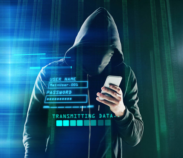 Hacking just got a little easier. Shot of an unidentifiable computer hacker using a smartphone while standing against a dark background. - Foto, imagen