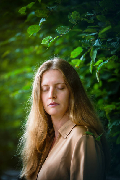 blond woman in nature with her eyes closed - Foto, afbeelding