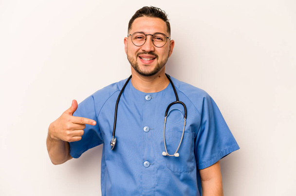 Ισπανόφωνος νοσοκόμος απομονωμένος σε λευκό φόντο που δείχνει με το χέρι σε χώρο φωτοτυπίας πουκάμισου, περήφανος και με αυτοπεποίθηση - Φωτογραφία, εικόνα