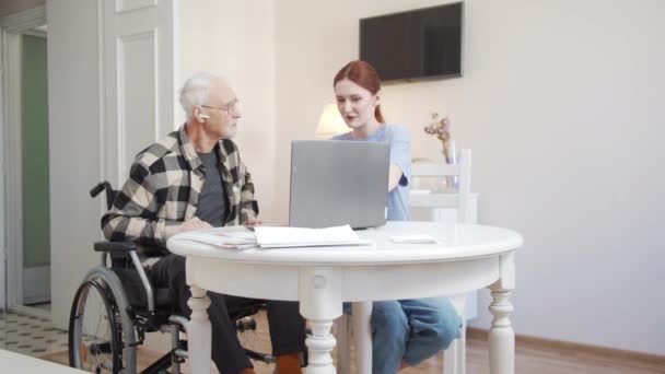 Vnučka představuje starému muži moderní technologie. Přehrává hudbu z počítače. Muž, který poslouchá zvuk přes bezdrátové sluchátko. Vysoce kvalitní 4K záběry - Záběry, video
