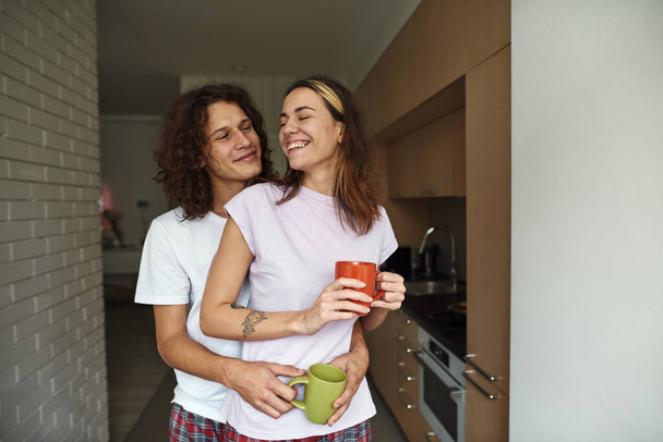 Man hug pleased girlfriend while they drink tea - Fotografie, Obrázek