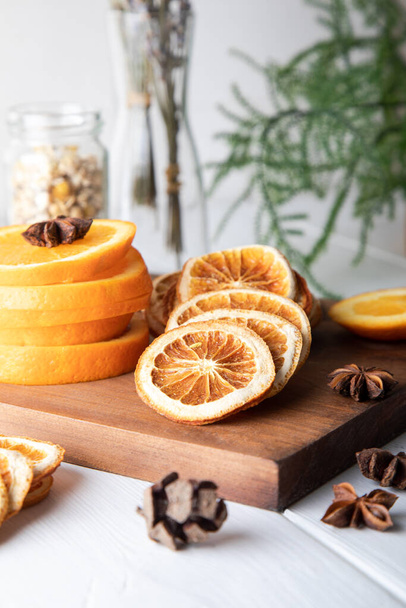 Dried orange slices, cinnamon and star anise on wooden board. - Фото, изображение