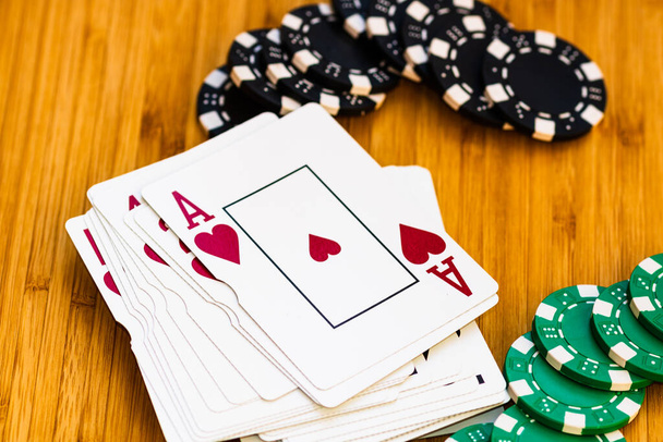 Karty do gry i żetony do pokera zbliżyć, izolowane na drewnianym stole. Koncepcja kasyna, ryzyko, szansa, szczęście lub hazard. - Zdjęcie, obraz