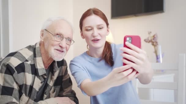 高齢者は,携帯で写真を撮ることができることに驚いています. 彼の大人の娘は彼にスマートフォンでセルフィーを取る方法を教えてくれます. 彼は気に入った。 高品質の4k映像 - 映像、動画