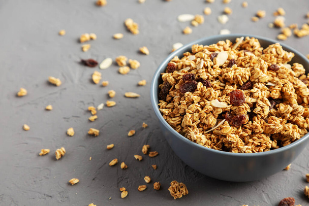 Homemade Granola with raisins and almonds  in a Bowl on a gray background, side view. Space for text. - Фото, изображение