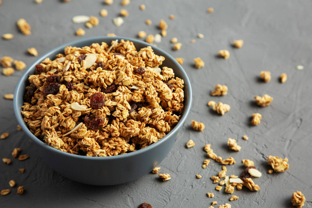 Homemade Granola with raisins and almonds  in a Bowl on a gray background, side view. Copy space. - Fotoğraf, Görsel