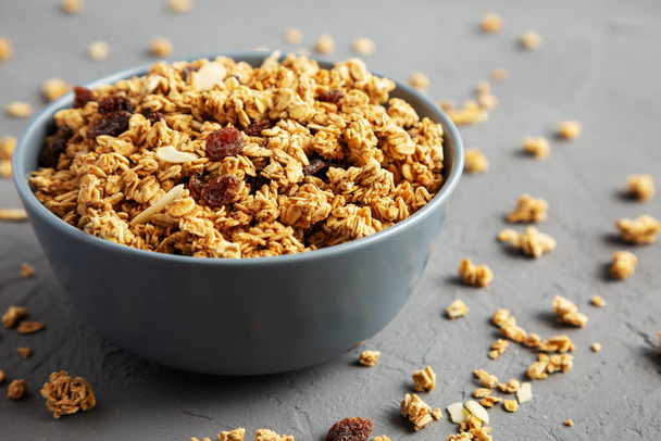 Homemade Granola with raisins and almonds  in a Bowl on a gray surface, side view.  - 写真・画像