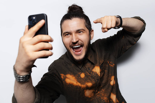 Happinesses young man want to touch screen of smartphone with finger, on white. - Foto, imagen
