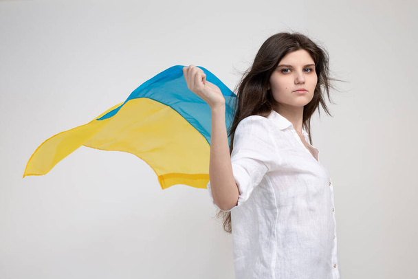 Ragazza ucraina con bandiera ucraina blu e gialla su sfondo bianco bianco. Spazio per il testo. Invasione russa dell'Ucraina, fermare la guerra. - Foto, immagini