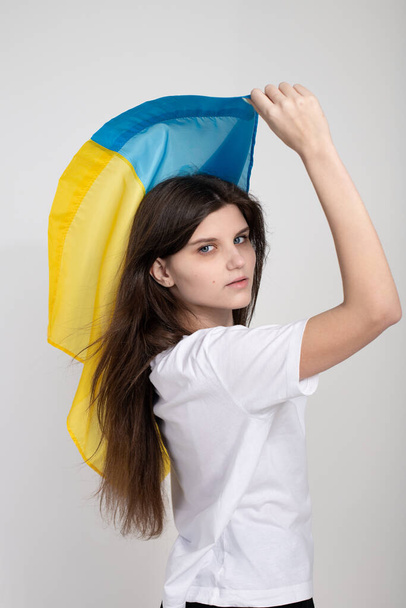 Beyaz izole edilmiş arka planda mavi ve sarı Ukrayna bayrağı olan Ukraynalı bir kadın. Ukrayna halkının dokunulmazlığının sembolü. Savaşı durdurun. Umut ve İnanç. - Fotoğraf, Görsel
