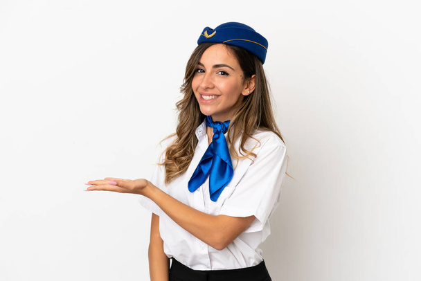 Stewardess eines Flugzeugs auf isoliertem weißem Hintergrund präsentiert eine Idee, während sie lächelnd in Richtung - Foto, Bild