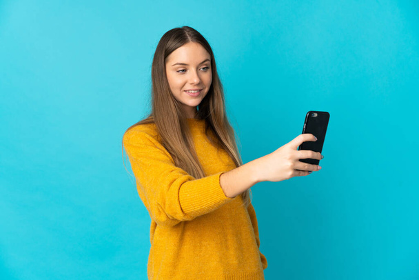Genç Litvanyalı bir kadın mavi arka planda izole edilmiş ve selfie çekiyor. - Fotoğraf, Görsel