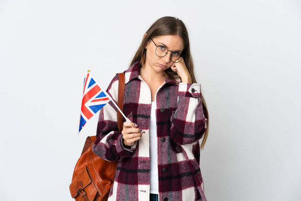 Young Lithuanian woman holding an United Kingdom flag isolated on white background with tired and bored expression - 写真・画像