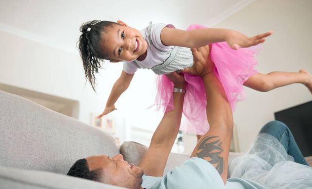 Look, Im a plane. Shot of an adorable little girl bonding with her father in the living room at home. - Фото, изображение