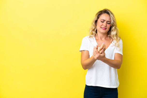 Young Brazilian woman isolated on yellow background suffering from pain in hands - Photo, Image