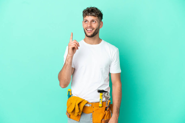 Young electrician blonde man isolated on green background pointing up and surprised - Photo, Image