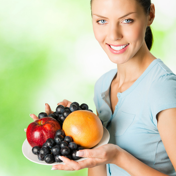 Young woman with plate of fruits, outdoors - Foto, immagini