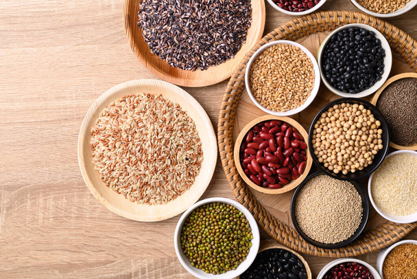 Varios cereales, granos, frijoles, legumbres y semillas en cuenco sobre fondo de madera, ingredientes alimentarios, vista superior de la mesa - Foto, imagen
